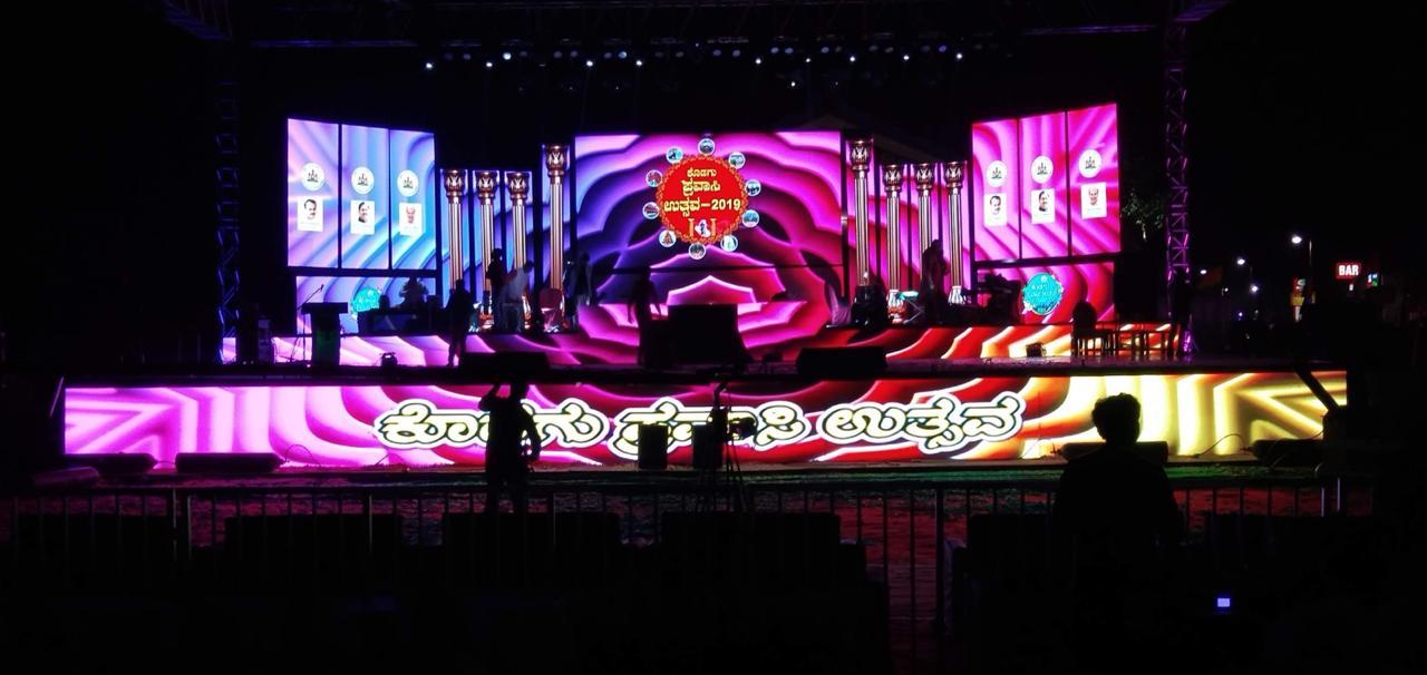Large outdoor cultural festival stage with LED walls and Kannada signage for public event in Karnataka