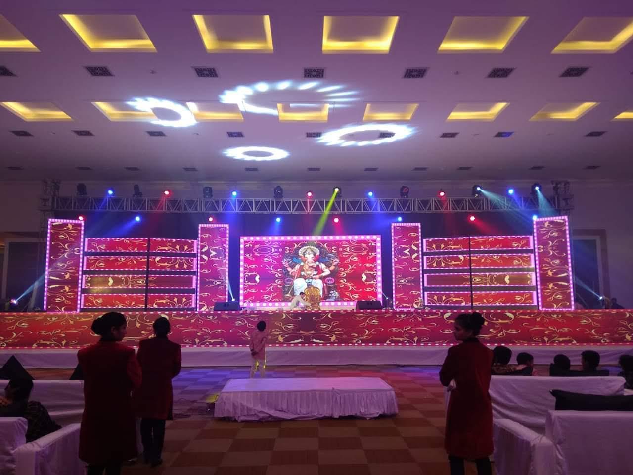 Indoor banquet hall with LED wall stage, moving head lights, and sound setup for cultural event in Bangalore