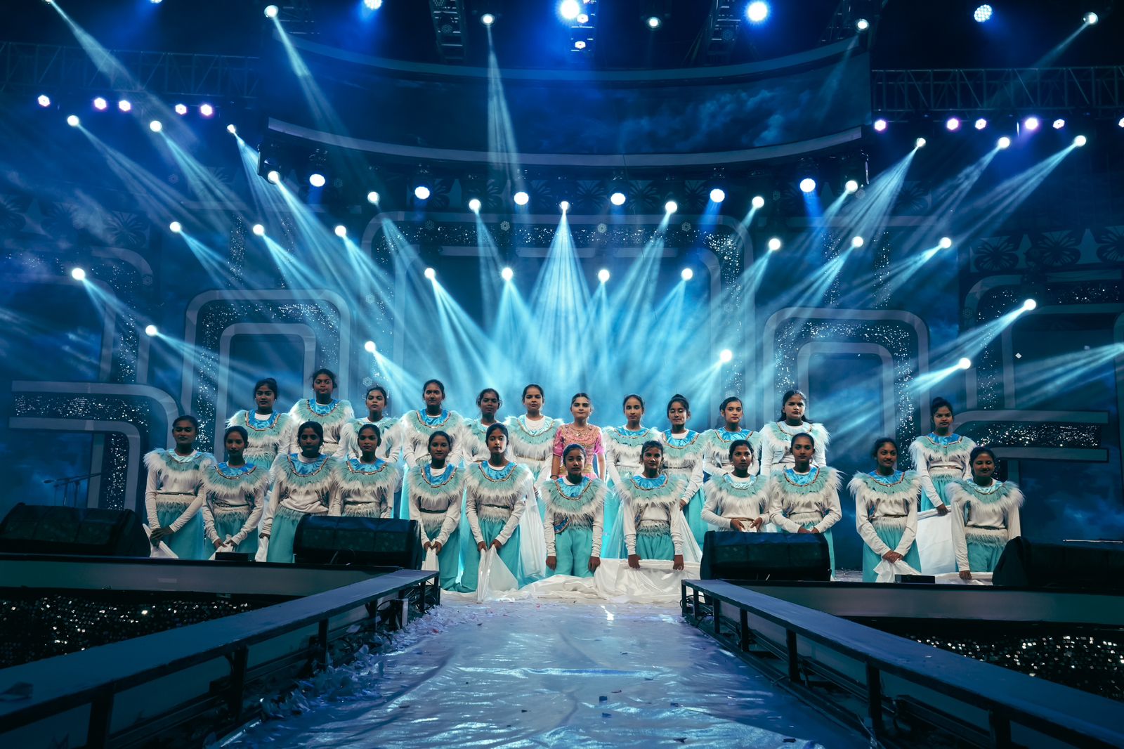 Choir and dance group performing under blue beam lighting with LED backdrop stage in Karnataka